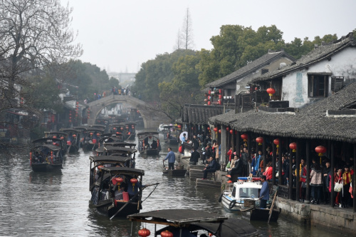 2月12日，游客乘坐游船在浙江西塘古鎮(zhèn)穿行。當(dāng)日是大年初五，位于浙江省嘉善縣境內(nèi)的西塘古鎮(zhèn)持續(xù)迎來(lái)大批游客。在春節(jié)期間，西塘景區(qū)每日舉辦祭灶神、水上婚禮等特色民俗活動(dòng)，讓游客感受到濃濃的傳統(tǒng)年味。新華社記者 黃宗治 攝