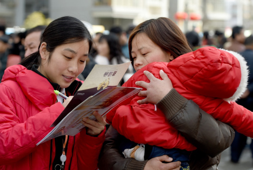 2月18日，在合肥市濱湖新區(qū)春風(fēng)行動第十二屆濱湖新區(qū)大型招聘會現(xiàn)場，回遷居民孫永華（右）抱著自己3歲大的孩子前來登記應(yīng)聘信息，她想找一個小時工的工作。新華社記者 郭晨 攝