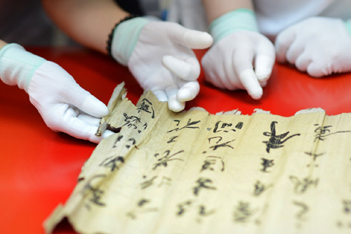 2013年7月15日，在天津博物館，2013年全國(guó)紙質(zhì)文物保護(hù)修復(fù)技術(shù)培訓(xùn)班學(xué)員在專家指導(dǎo)下展開(kāi)受損的古舊字畫(huà)。