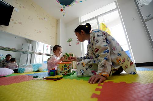 3月3日,西安兒童福利院的工作人員陪伴收治的棄嬰玩耍。新華社記者 李一博 攝