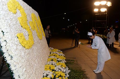 3月4日,一名醫(yī)務工作人員在昆明市市級行政中心廣場為逝者獻上鮮花。 新華社發(fā)(胡超 攝)
