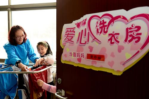 3月10日,在威海市經(jīng)濟技術開發(fā)區(qū)新都小學,愛心洗衣房“當值媽媽”梁玲麗和留守兒童一起晾曬衣服。為解決留守兒童生活中的一些實際困難,山東省威海市經(jīng)濟技術開發(fā)區(qū)新都小學在校園里建立了“愛心洗衣房”,每周“當值媽媽”收集并清洗留守兒童的衣物,將關愛落到行動中。新華社記者 郭緒雷 攝 3月10日,在威海市經(jīng)濟技術開發(fā)區(qū)新都小學,愛心洗衣房“當值媽媽”梁玲麗在