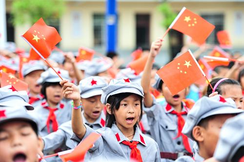 6月3日,在授旗授牌儀式上,康克清紅軍小學(xué)的學(xué)生在揮舞國旗。新華社記者 李琰 攝