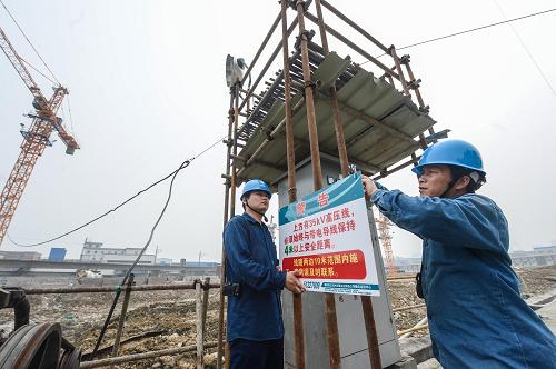 6月18日,電力工作人員在一處工地懸掛警示標志。新華社記者 徐昱 攝
