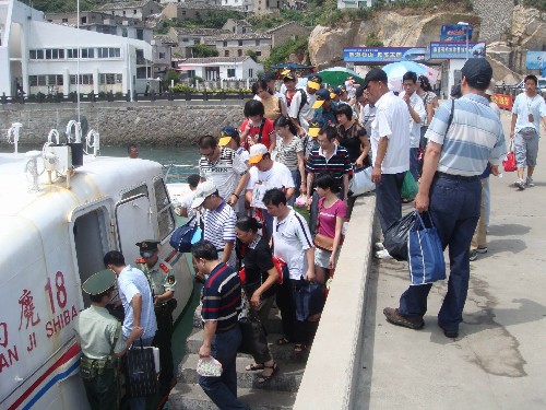 7月17日,在溫州南麂島,游客們?cè)谀削溥叿琅沙鏊俦膸椭掠行虻峭С冯x。當(dāng)日,為應(yīng)對(duì)來(lái)勢(shì)洶洶的臺(tái)風(fēng)“海鷗”,浙江省溫州市邊防支隊(duì)南麂邊防派出所啟動(dòng)防臺(tái)工作預(yù)案,會(huì)同當(dāng)?shù)劓?zhèn)政府做好南麂島游客的撤離工作。截至17日13時(shí),南麂島上的600余名游客已安全撤離。 新華社發(fā)(吳水斌 攝)