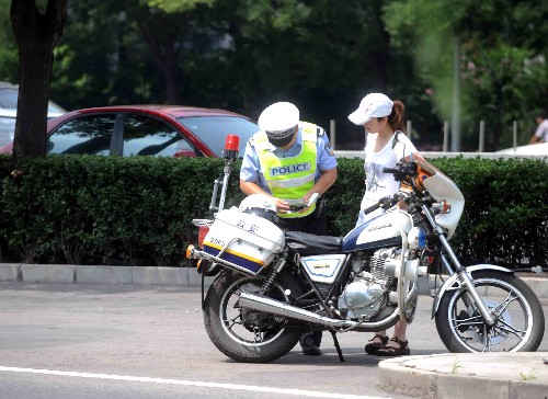 7月20日,一名交警在北京復(fù)興門(mén)附近對(duì)一名違反單雙號(hào)限行規(guī)定的車(chē)主進(jìn)行處罰。新華社記者 羅曉光 攝