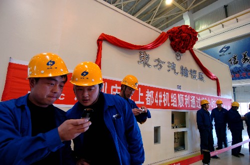兩名工人在上都電廠新投產(chǎn)的4號機組旁欣賞自己與汽輪機的留念照片(11月10日攝)。 11月10日15時16分,隨著北方電力上都電廠4號機組順利通過168小時試運行,內蒙古“西電東送”北通道北京奧運會保電項目的第二臺機組正式投入商業(yè)運行。 2004年8月開工建設的上都電廠二期工程,是內蒙古自治區(qū)2008年奧運保電重點工程,其中3號機組已于2007年8月31日移交生產(chǎn)。隨著4號機組投產(chǎn),上都電廠的裝機容量達到240萬千瓦。 新華社記者張領攝