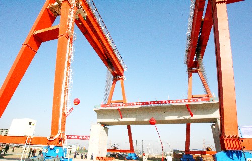 12月9日,在京滬高速鐵路蘇州制梁場,京滬高鐵蘇州段的首榀箱梁被兩臺大型提梁機穩(wěn)穩(wěn)提升至橋墩上。新華社發(fā)(王建中 攝)